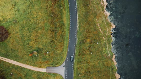 Top View, Drone Flying High Above Black Car Driving Along Autumn Coastline Road Near Beautiful alt