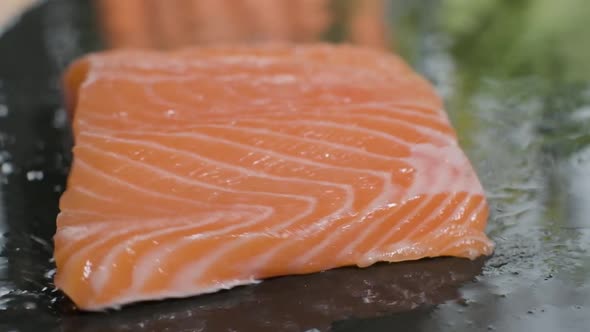Fresh Salmon Fillet Falling Into Wet Black Stone Board. - close up, slow motion alt