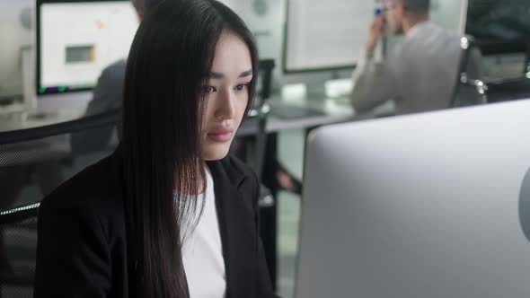 Attractive Asian Woman Working on Decktop Computer While Working in Big Open Space Office alt