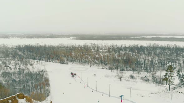 Lower Station Ski Surface Lift on Snowy Slope Against Forest alt