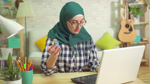 Young Muslim Woman Searching the Internet for an Asthmatic Inhaler alt