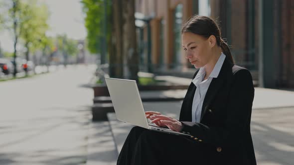 Woman in Business Suit Working on Laptop Outdoors alt