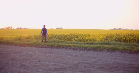 Agriculture - Farmer Walking on Field Examining Crops at Farm at Dusk alt