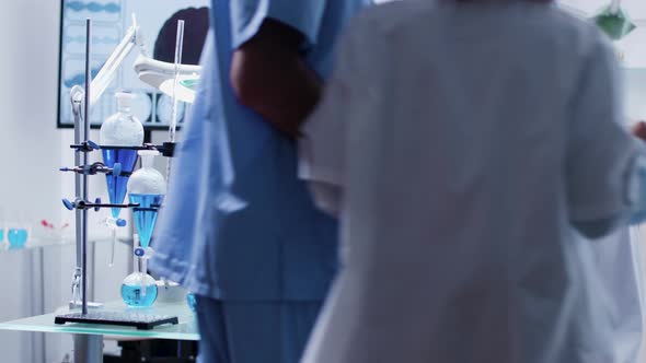 In Busy Research Center Mature Scientist Analyzes Samples From Tubes alt