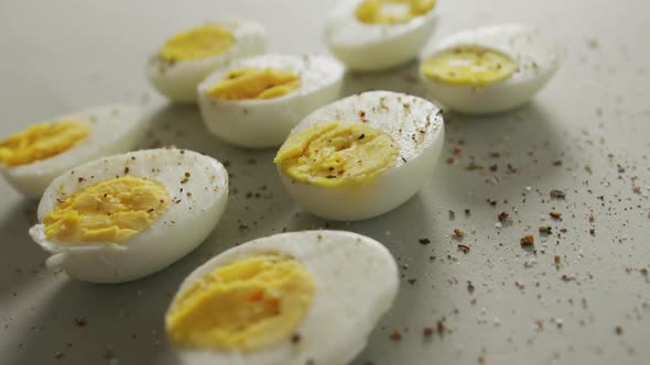 Video of close up of peppered halves of hard boiled eggs on grey background alt