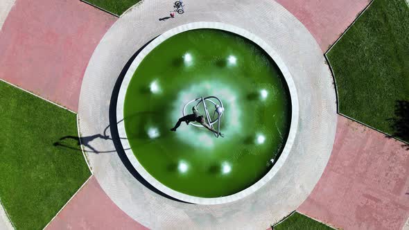View of unusual round fountain with bright green water in golden evening light alt
