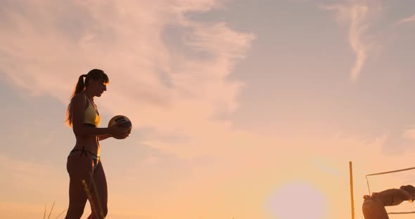 A Beautiful Woman in a Bikini with a Ball at Sunset Is Getting Ready To Do Serve Jump on the Beach alt