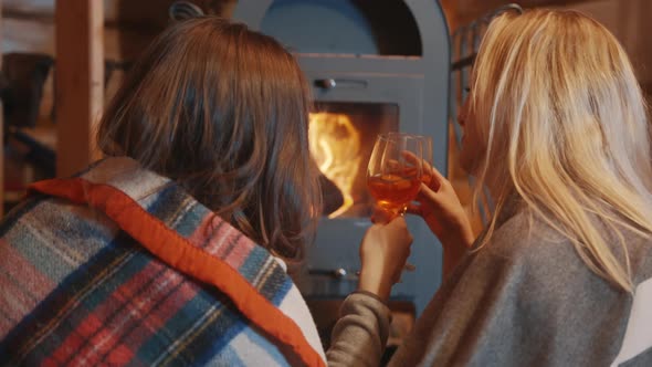 Two Young Women Lesbian Couple Relaxing Near the Fireplace and Drinking Wine in the Cozy Home alt