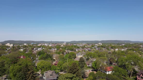 Aerial view over established midwest city with diverse architecture and tree lined streets.