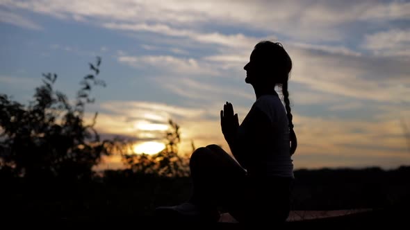 Silhouette of a woman praying with Amazing dramatic sky sunset background. alt
