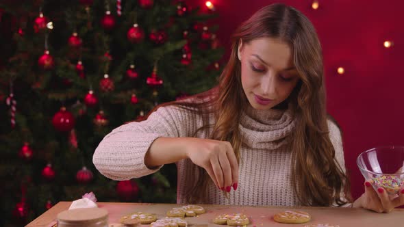 Christmas Baking. Pretty Woman Decorate Gingerbread Cookies with Sugar Sprinkles