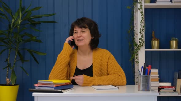 Middle Aged Businesswoman or Freelancer Talking Mobile Phone in Home Office