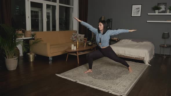 Young Asian Woman Doing Yoga Exercises in her Cozy Dark Room at Home in the Evening alt