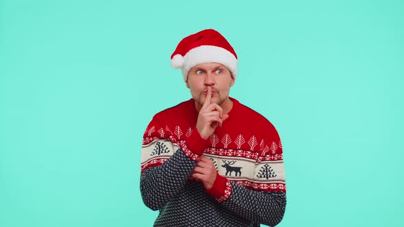 Man Wears Red Christmas Sweater Presses Index Finger to Lips Makes Silence Gesture Sign Secret alt