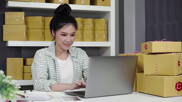 happy woman working with her laptop computer and courier parcel box at home office