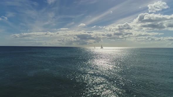 Aerial dolly, sailing boats silhouette on pacific Ocean, Sunlight reflection on Water surface alt