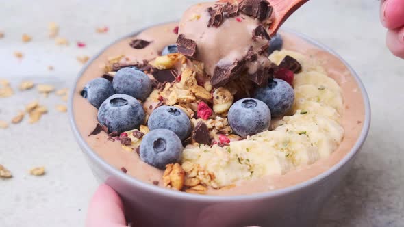 Chocolate banana smoothie bowl with granola, berries and hemp seeds.