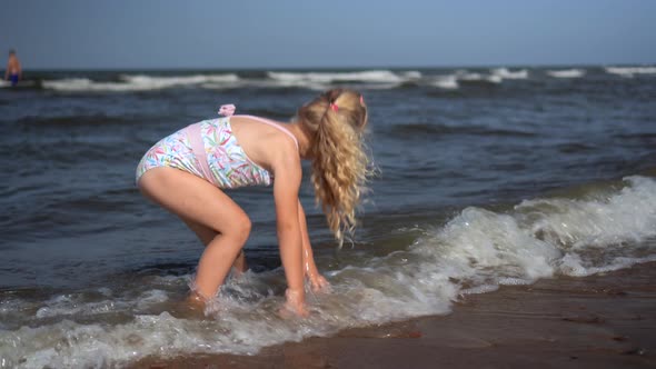 5 Years Old Girl in Swimsuit Playing with Sea Waves at Coastline