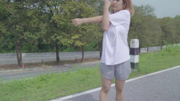 Asian runner woman legs warming and stretching her arms to ready for running on street.