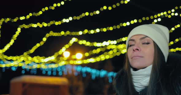Pretty Girl Walks Along the Night Alley Decorated with Garlands of Lights alt