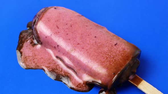 The chocolate ice cream sundae lies on a blue background and melts slowly. 4K video food close-up. alt