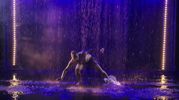 A Silhouette of a Sporty Man Showing the Technique of Capoeira Martial Art in the Rays of Blue Light alt