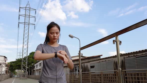 Beautiful young Asian woman athlete looking at heart rate on a smartwatch.