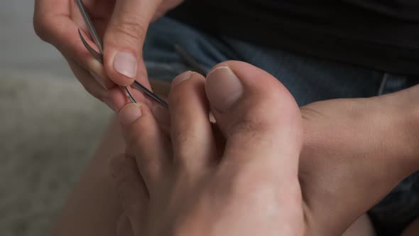 Woman Is Polishing Husband's Nails on Toes Using File Closeup View