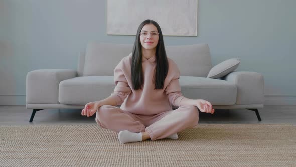 Young Caucasian girl sitting on floor in lotus position and doing yoga.