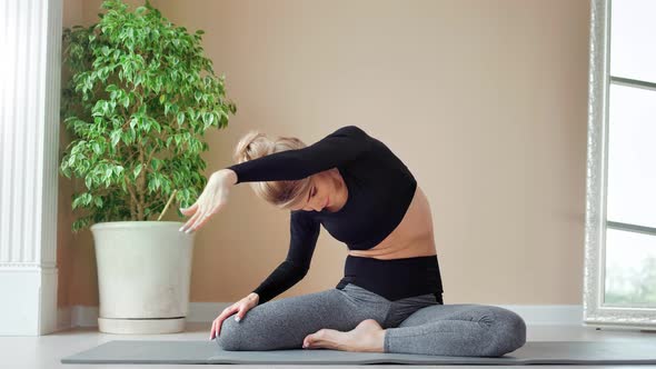 Athletic Young Woman Showing Slim Flexible Body Sitting on Mat at Home Full Shot alt