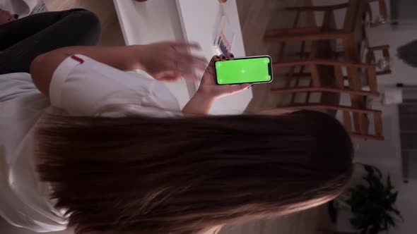 Home Isolated. Back View of Brunette Holding Chroma Key Green Screen Smartphone Watching and Chating