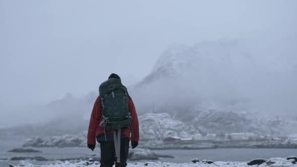 Hiker Walking Through Snow Towards Fjord alt