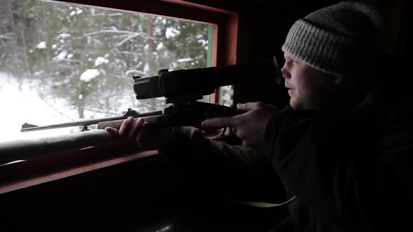 A Hunter with a Gun on an Observation Tower for Hunting in the Forest