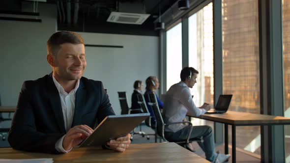 Smiling Handsome Boss Enterpreneur with Tablet PC with Call Center alt