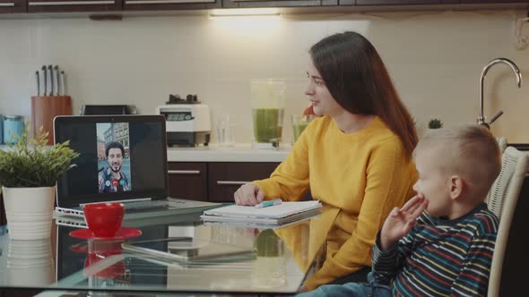 Young Mother and a Son Making Video Call with Man on Computer alt