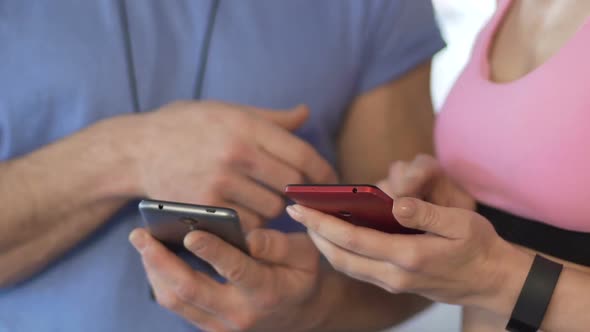 Female and Her Personal Trainer Synchronizing Cellphones Before Starting Workout alt