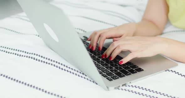 Hands with Red Nail Polish of Young Woman Pressing Laptop Keys