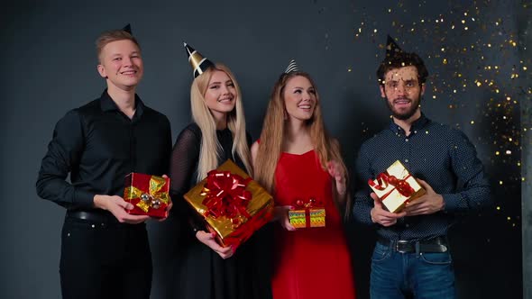 Company of Beautiful People Posing with Bright Gift Boxes in Their Hands. alt