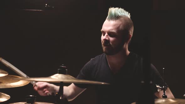 Drummer performing in a studio setting. alt