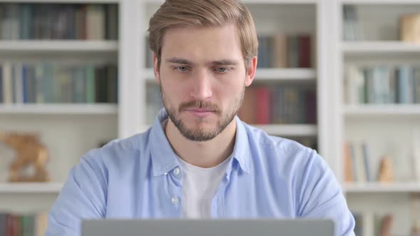 Portrait of Man Showing Thumbs Down While Using Laptop alt