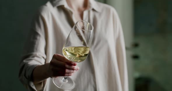 Glass of White Wine Shimmers Beautifully in the Light in a Woman's Hand