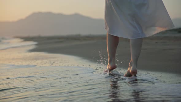 Young woman walking on the waves on the beach in summer alt