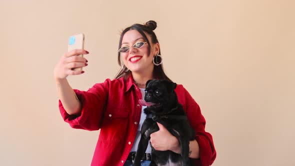 Stylish trendy woman makes a selfie online life stream video call chat on mobile phone with her pet alt