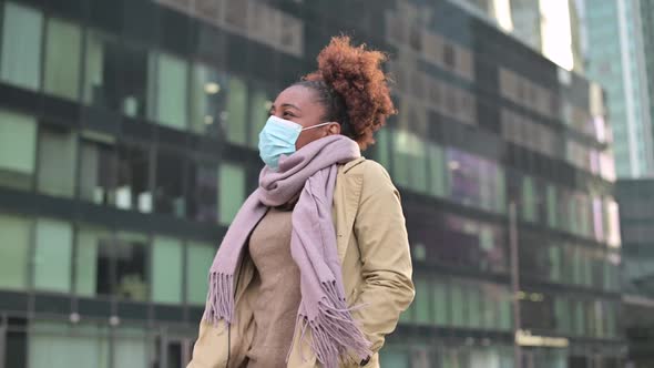Young black woman putting on medical mask and then taking off against cityscape alt