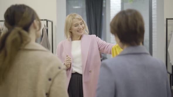 Positive Happy Woman Showing Yellow Blouse To Friends in Shopping Mall and Leaving To Dressing Room alt