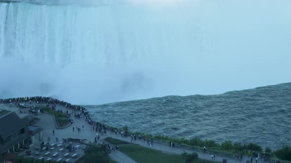 A close-up shot of people looking out over Niagara Falls from the Canadian side. alt