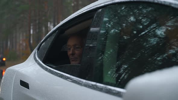 a Man with Glasses Looks Out From the Rear Window of a Car