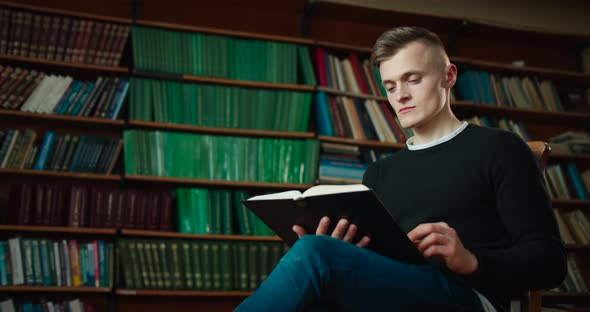 The Guy Is Slowly Looking Through the Book That Interested Him. The Guy Is Sitting Against the alt