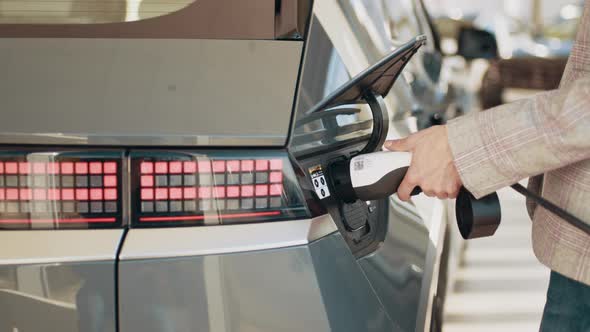 Close Up of Female Hands Using Remote Control to to Charge the Modern Electric alt