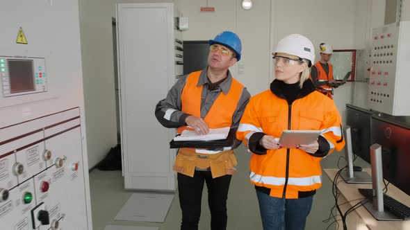 Technician and Engineer with Tablet and Papers at Substation